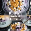 Blueberry shortcake fluff salad is shown in two bowls with creamy purple fluff, blueberries, mini marshmallows, and cake cubes.
