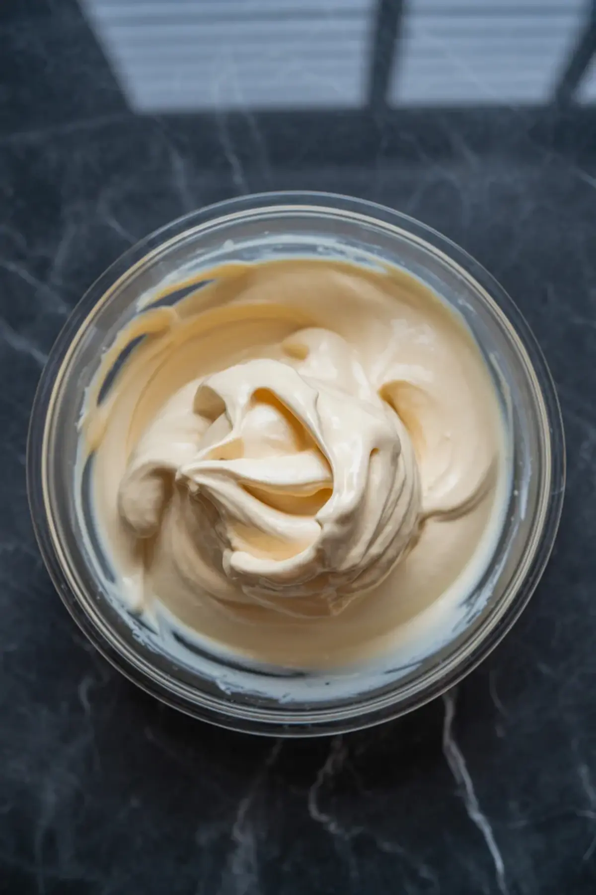 The creamy vanilla base for blueberry fluff salad is whipped smooth in a glass bowl.