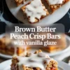 Brown butter peach crisp bars with vanilla glaze on plates, showing a thick peach filling, oat crumble topping, and white glaze drizzled over each bar.