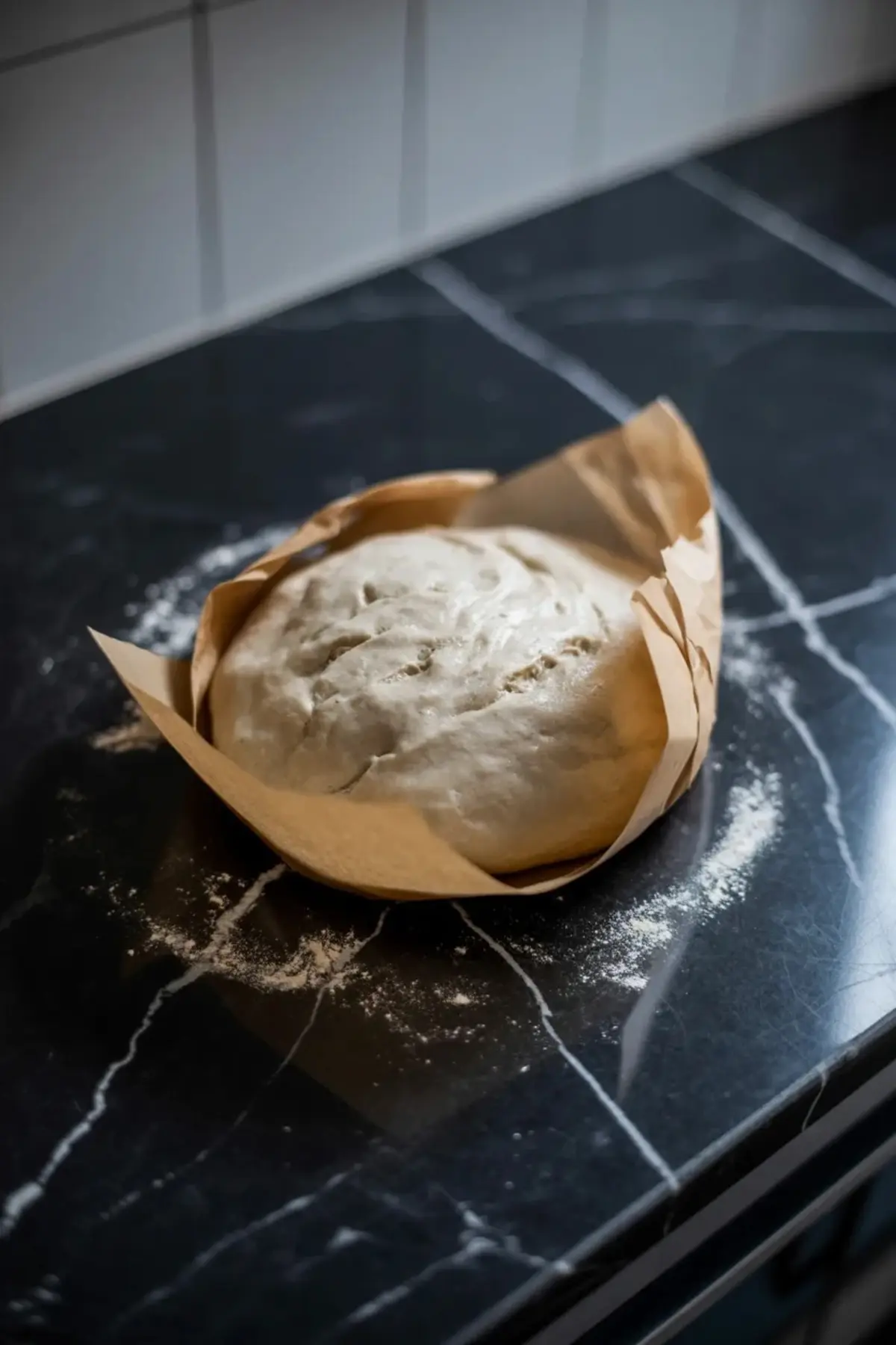 Galette dough rests in parchment on a dark counter before rolling and shaping.